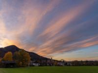 Fächerförmige Wolken leuchten orange am Abendhimmel über Aschau